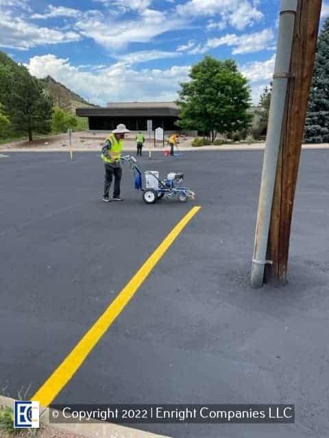 Worker painting parking stall lines in a parking lot in Aurora