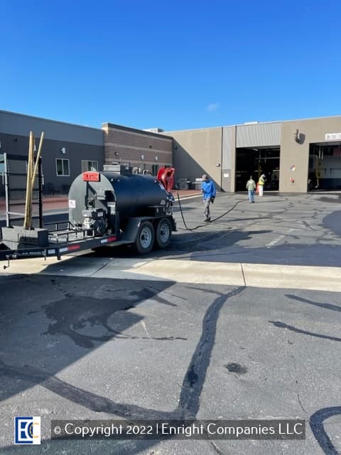 Sealcoating team spraying seal coat on a parking lot in Aurora, CO