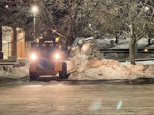 Skid steer removing snow from business parking lot