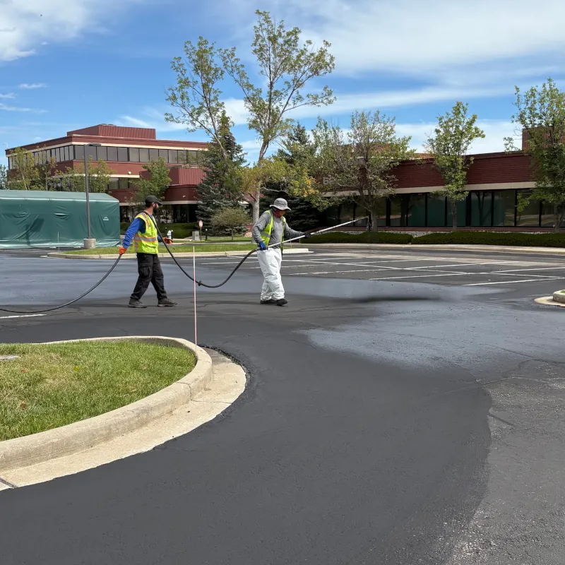 crew spraying sealcoating on parking lot